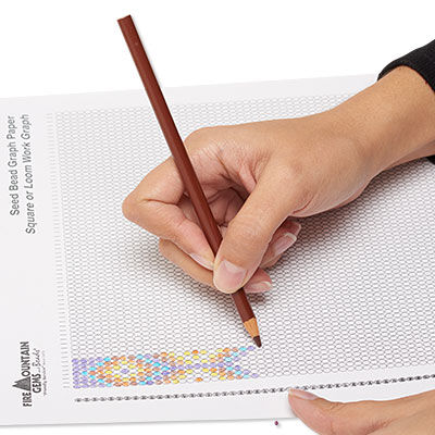 Hands filling out looming graph paper